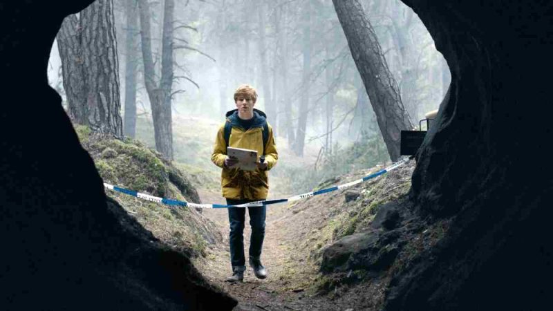 Dark, un băiat cu o hartă în mână in fața unei intrări dintr-o peșteră