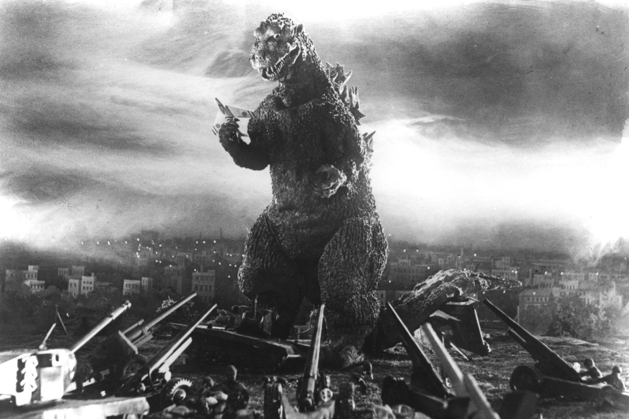 Personajul SF Godzilla înconjurat de oameni cu tunuri